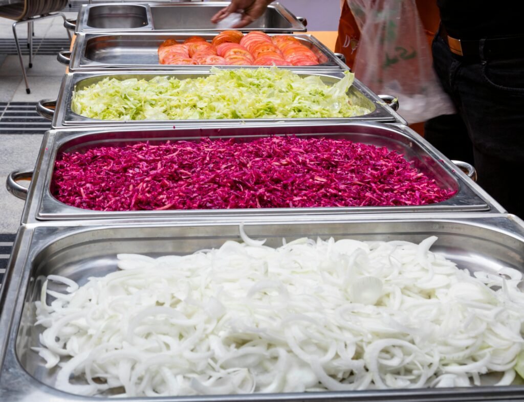 A variety of fresh vegetables in trays at a buffet. Perfect for salads or dishes.